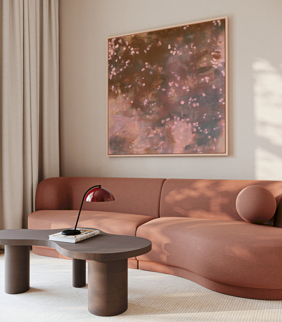 A large framed abstract painting with warm brown, bronze, and pink tones hangs on a beige wall above a curved terracotta-colored sectional sofa in a modern living room setting.