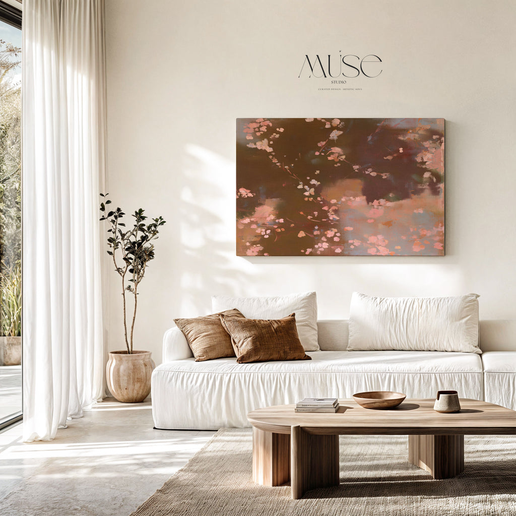 A large rectangular wall art print featuring an abstract floral scene in earthy brown, beige, and pink tones, displayed above a white sofa in a bright, modern living room.