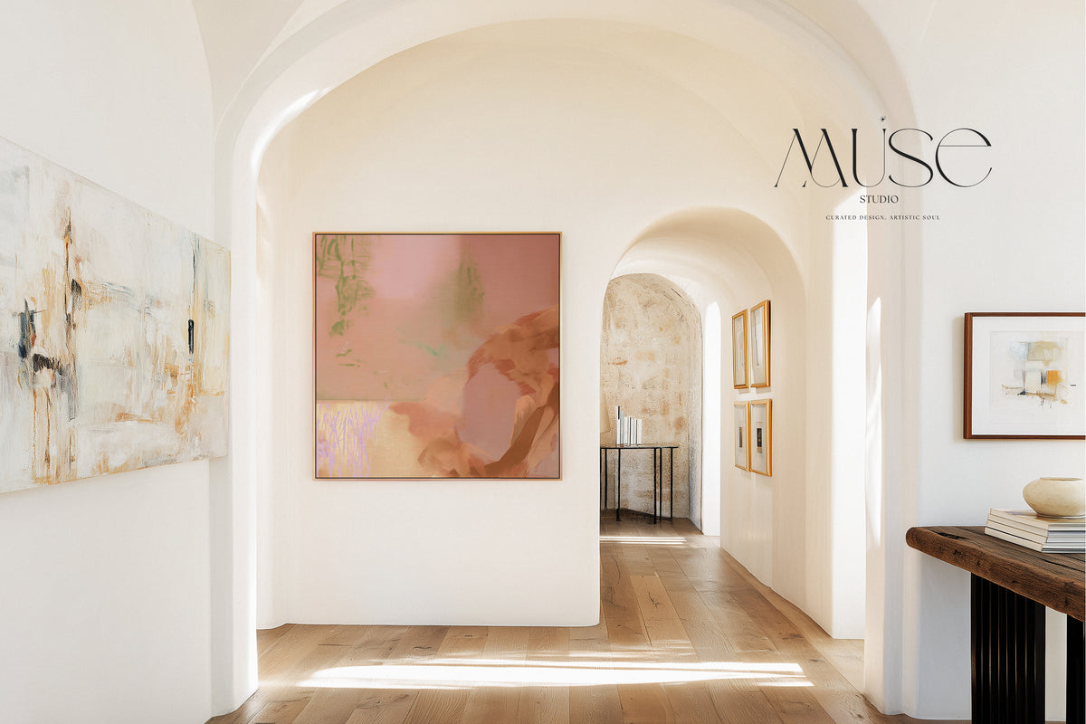 Framed terracotta and sage abstract wall art viewed through an archway in a bright hallway with wood floors