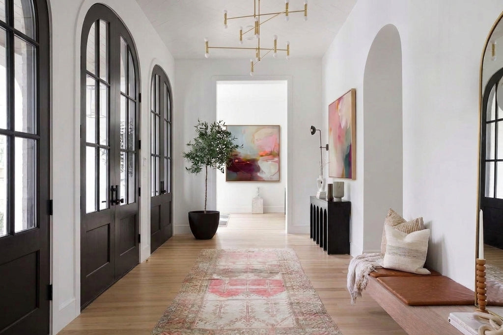 Square abstract painting with deep plum, dusty rose, and sky blue accents hanging at the end of a long hallway.