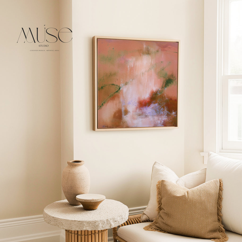 Framed square terracotta and peach canvas wall art mounted in a sunlit organic modern living space with a stone side table and ceramic vase.