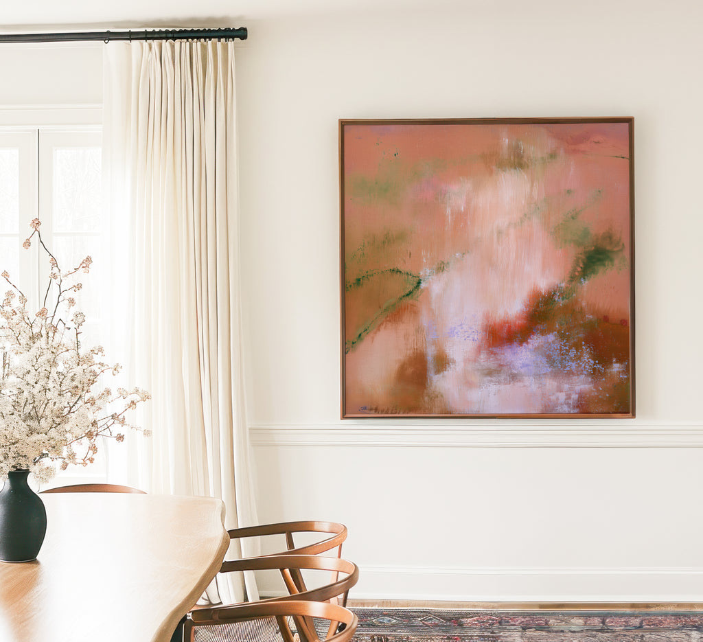 Oversized framed square canvas print displayed in an elegant dining room above white wainscoting next to tall linen drapes and a wooden table.
