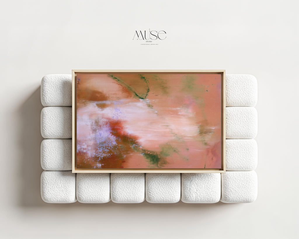 Large framed terracotta and blush abstract canvas art centered above a modern white textured bouclé sofa in a minimalist living room setting.