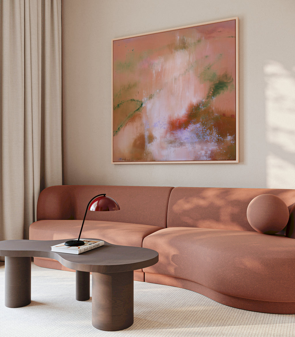 Large framed square autumnal abstract art hanging above a curved terracotta sofa in a modern minimalist living roo