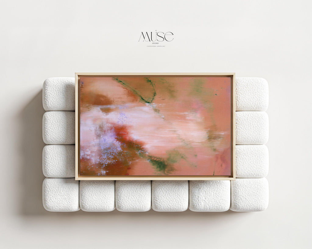 Large framed terracotta and blush abstract canvas art centered above a modern white textured bouclé sofa in a minimalist living room setting.
