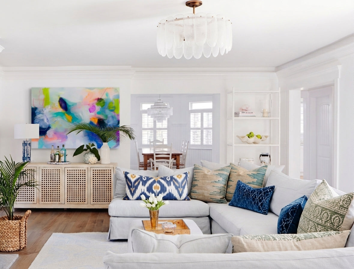 Large horizontal abstract canvas art featuring vivid blue, teal, magenta, and lime green brushstrokes hanging on a white living room wall above a wooden credenza.