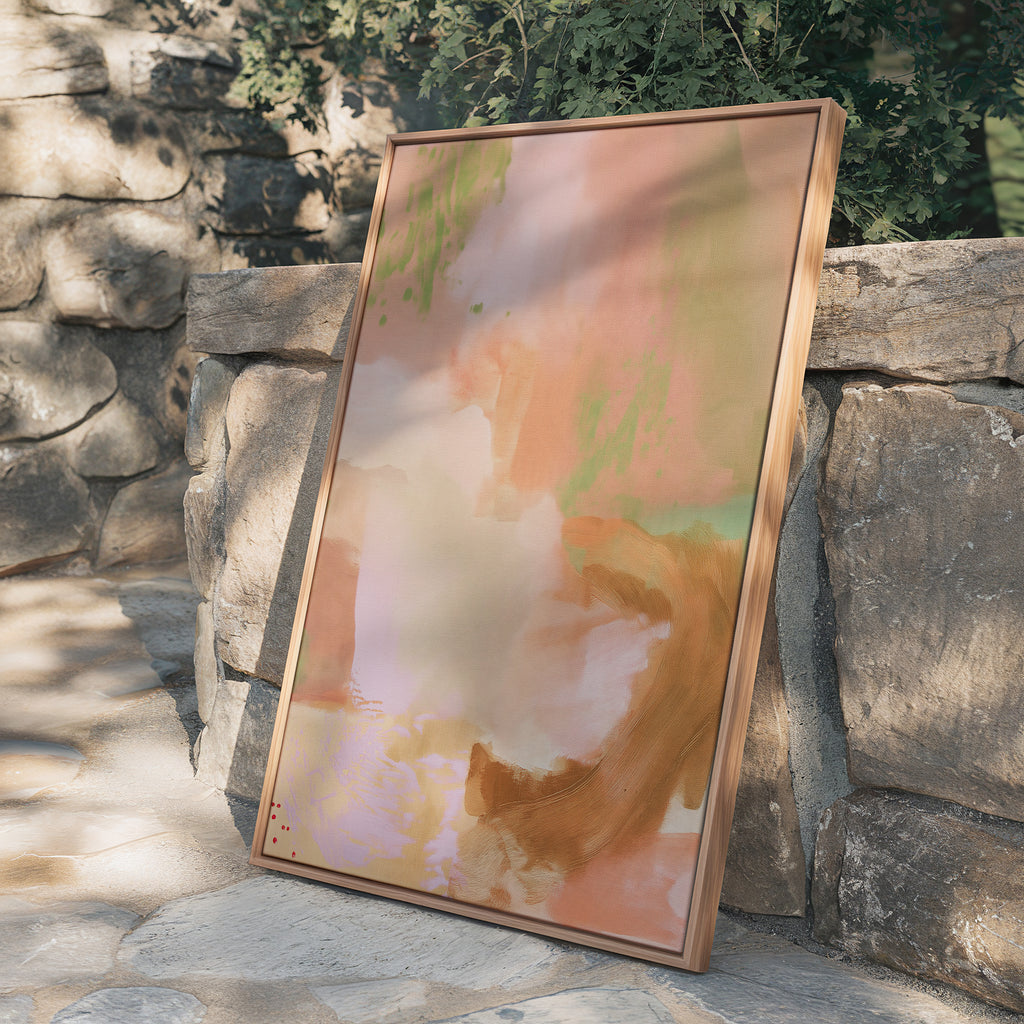 Vertical framed abstract canvas print leaning against a rustic stacked stone garden wall surrounded by dappled natural sunlight, foliage shadows, and stone patio paving.