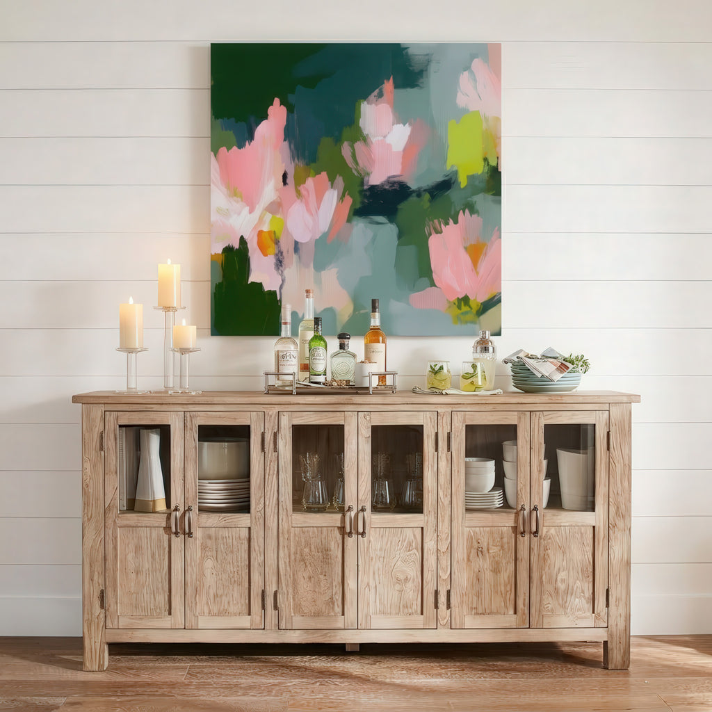 Garden Bloom No. 1039 canvas wall art displaying an organic, abstract floral design in shades of blush pink, vibrant chartreuse, and dark green, shown framed above a rustic wooden sideboard.