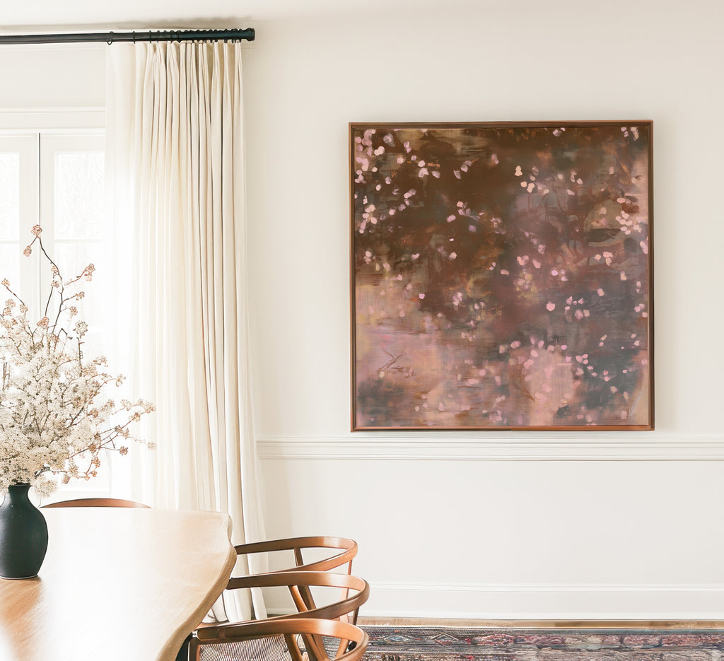 Framed square canvas art, earthy brown moody botanical print Oaken Petal No. 1124 hung on a soft neutral wall beside flowing linen curtains and a modern dining space