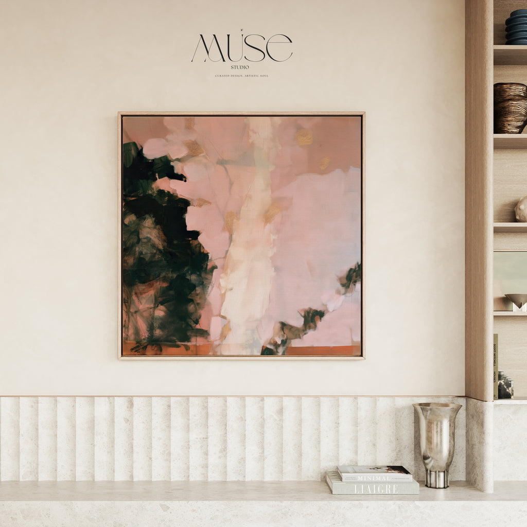 Large square framed abstract art in soft blush pink, dark forest green, and gold accents hanging on a textured off-white wall above a fluted wooden credenza in a warm minimalist living room.
