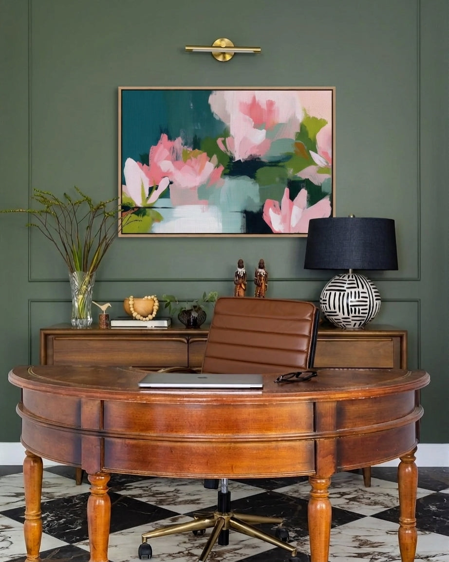 Horizontal framed canvas artwork featuring abstract pink floral water lilies on a dark teal and green background, displayed above a desk by Muse Studio & Co.
