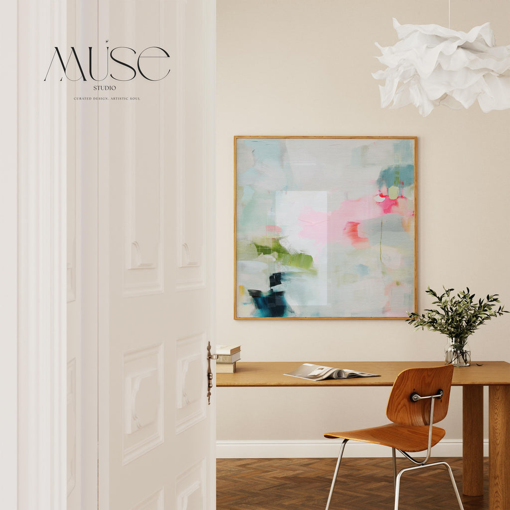 Framed abstract canvas wall art in blush pink, blue, green, and soft neutral tones. Square modern painting with expressive brushstrokes and light color palette. Ideal for bedrooms, home offices, or styled spaces seeking a feminine and fresh decor piece. Presented in a natural wood frame, this soft contemporary artwork adds gentle movement and colorful balance to curated interiors. A Muse Studio original designed for designer-led spaces.