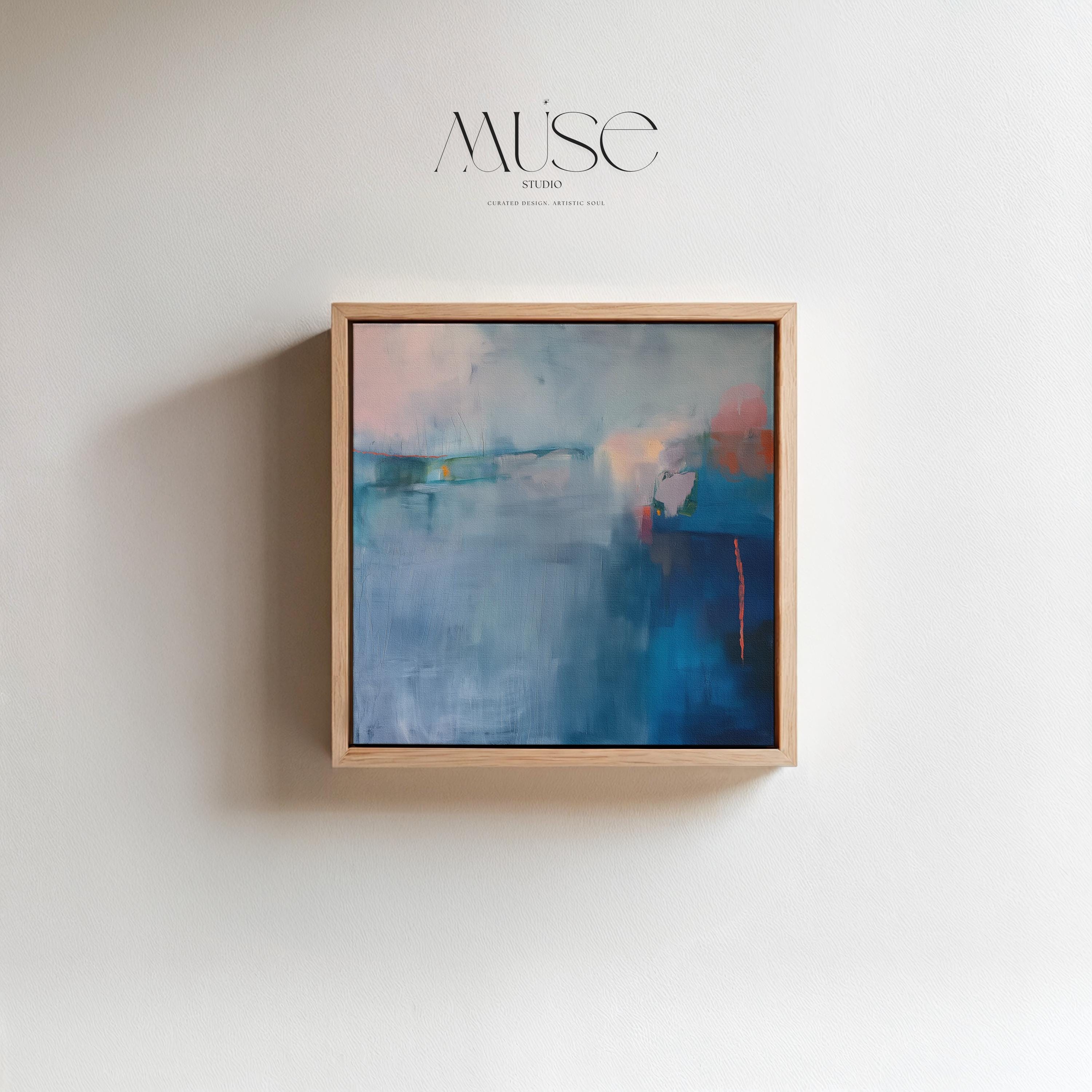 Square framed canvas wall art featuring a moody abstract landscape in rich blue, indigo, blush, and coral tones. This modern piece adds emotional depth and painterly texture to any room. Ideal for coastal interiors, minimalist spaces, or moody decor palettes. Framed in natural wood and displayed on a clean white wall, perfect for offices, living rooms, or curated art walls. Muse Studio original design for refined home styling.