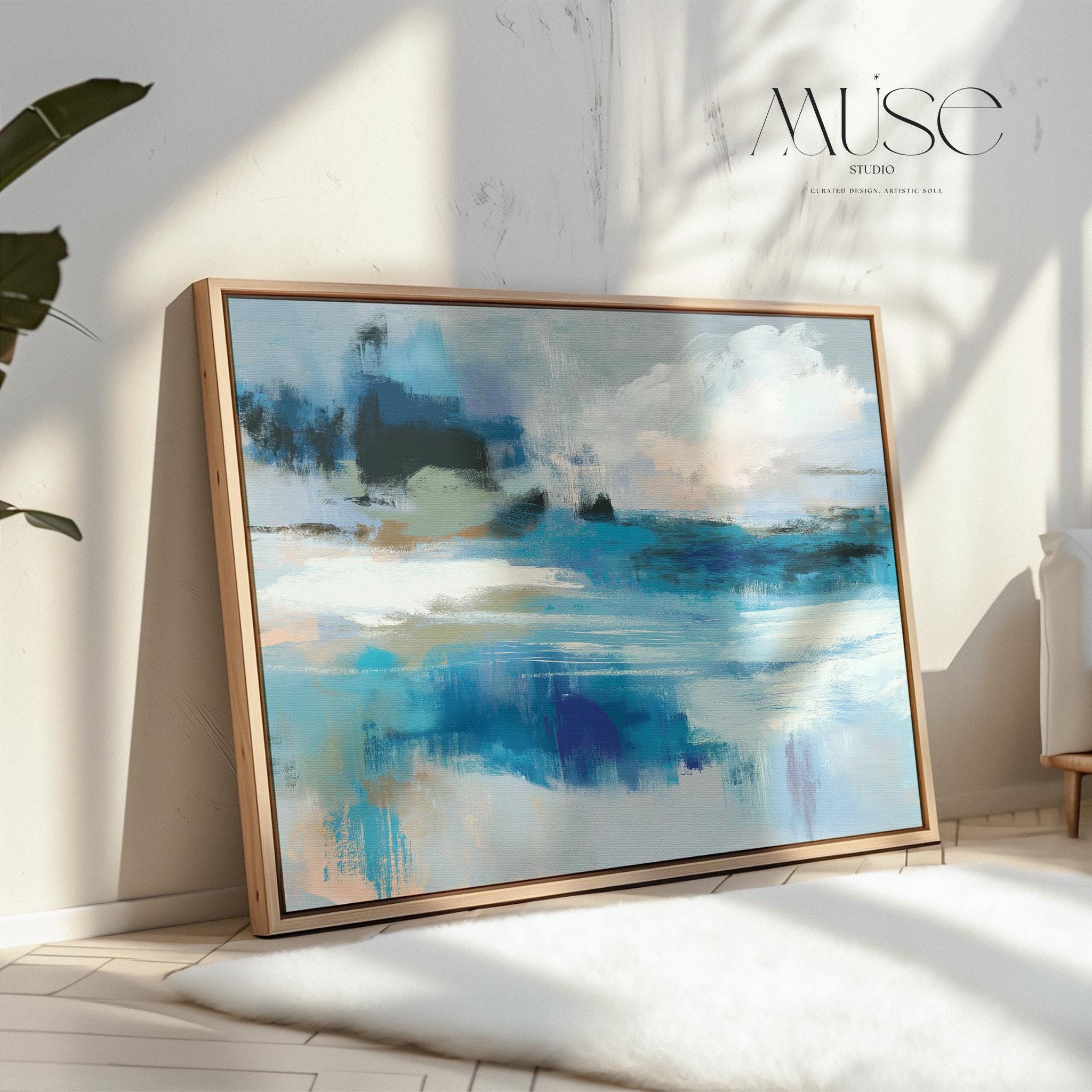 Framed horizontal wall art featuring soft painterly layers of ocean blue, sand beige, and sky tones in a modern coastal abstract. Ideal for beach house living rooms, transitional interiors, or above sofa placement. Available as a fine art poster or canvas wall art for curated, color-forward decor.