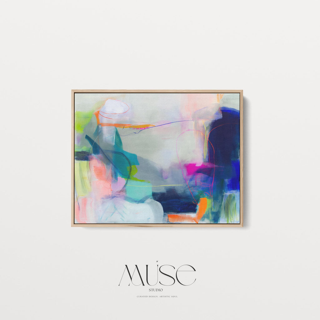 Large horizontal abstract wall art in bright blue, neon pink, teal, and multicolor tones displayed above a white sofa in a modern neutral living room with natural light and minimal decor. Vibrant color pop artwork available as framed canvas or fine art print by Muse Studio.