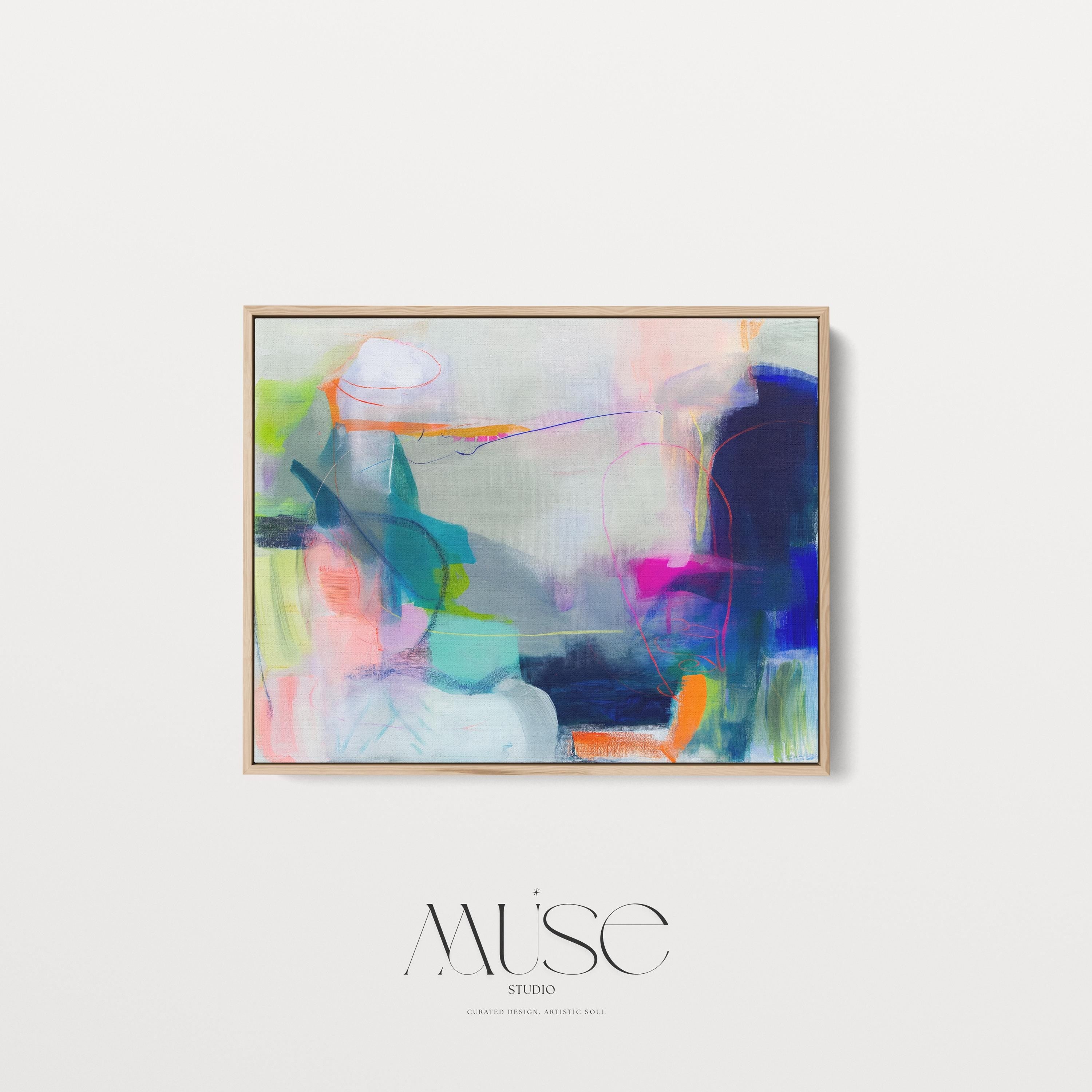 Large horizontal abstract wall art in bright blue, neon pink, teal, and multicolor tones displayed above a white sofa in a modern neutral living room with natural light and minimal decor. Vibrant color pop artwork available as framed canvas or fine art print by Muse Studio.