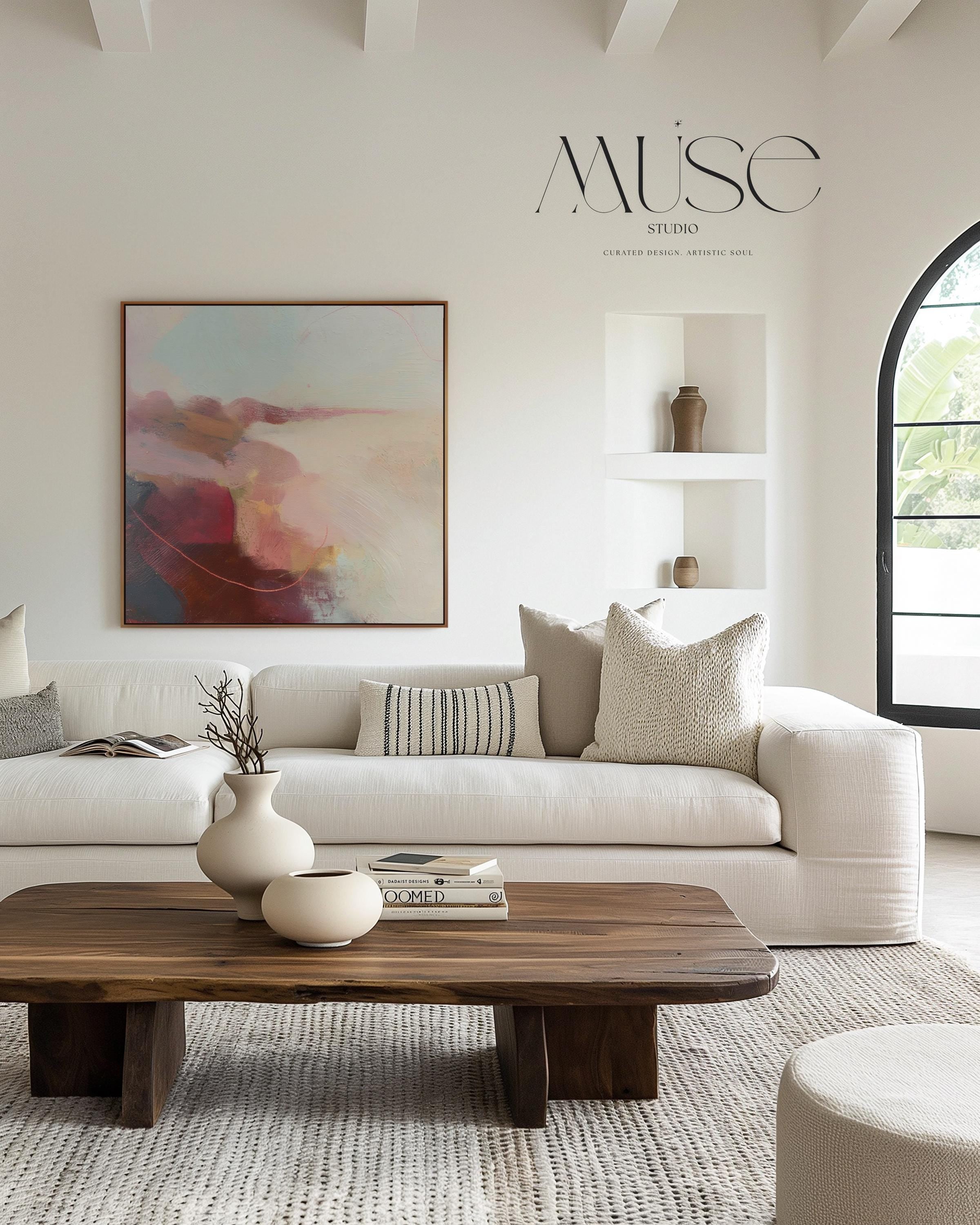 Large square abstract wall art in blush, burgundy, peach, and soft teal tones displayed above a modern black credenza with an Eames lounge chair in a light, elegant room. Warm contemporary abstract canvas for living room or designer interiors, available as framed wall art or canvas by Muse Studio.