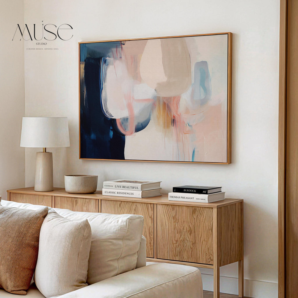 Large framed canvas wall art featuring blush, peach, ivory, muted blue, and navy tones in a horizontal abstract giclée print. Designed in muted neutral style with transitional and soft contemporary appeal, this artwork is perfect for living rooms, dining rooms, or bedrooms. Its calming palette and painterly textures bring balance and elegance to interiors. Available as a floating framed canvas giclée print in multiple large sizes.