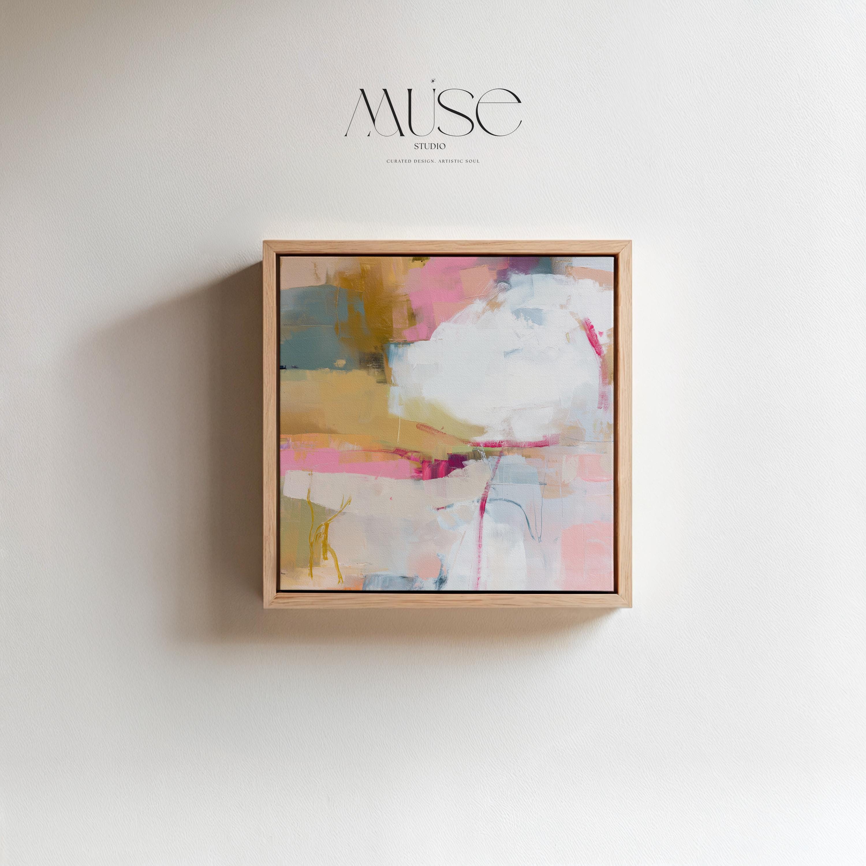 Square abstract wall art in soft pink, mustard, white, and teal tones framed in natural wood and displayed on a clean white wall. Light pastel contemporary artwork with gentle brushwork, ideal for modern living rooms, bedrooms, or designer interiors. Available as framed canvas or giclée print by Muse Studio.