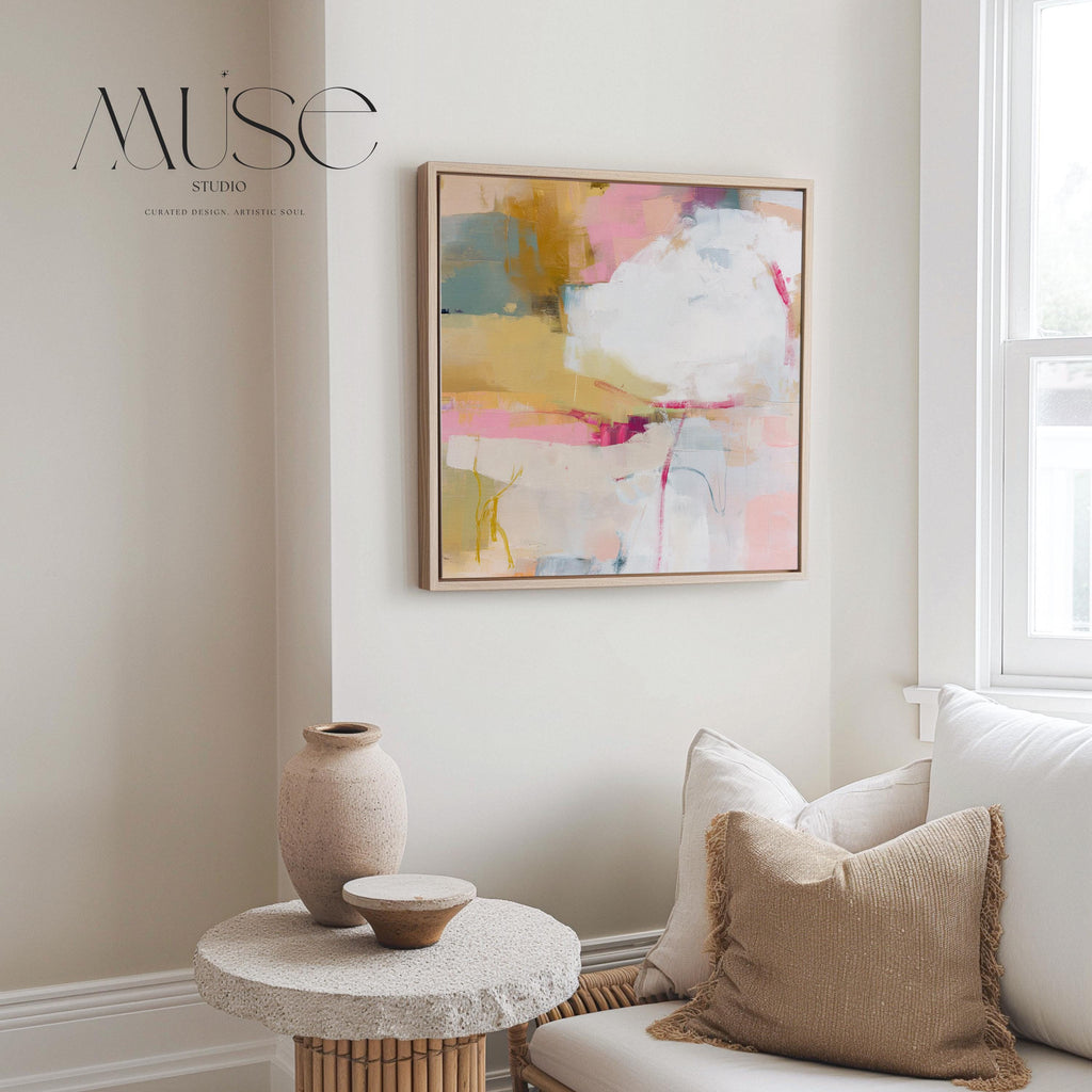 Square abstract wall art in soft pink, mustard, white, and teal tones framed in natural wood and displayed on a clean white wall. Light pastel contemporary artwork with gentle brushwork, ideal for modern living rooms, bedrooms, or designer interiors. Available as framed canvas or giclée print by Muse Studio.