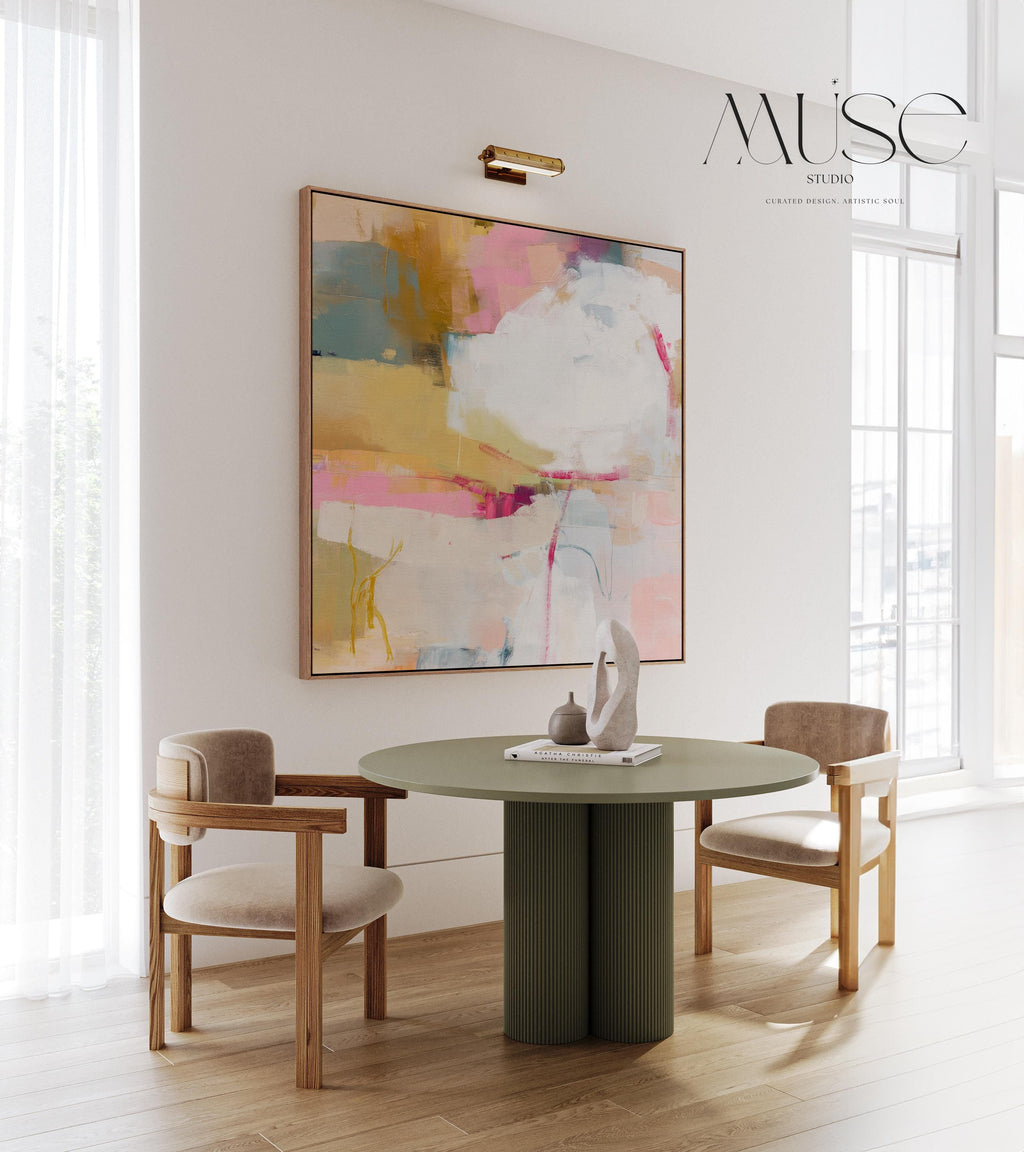 Square abstract wall art in soft pink, mustard, white, and teal tones framed in natural wood and displayed on a clean white wall. Light pastel contemporary artwork with gentle brushwork, ideal for modern living rooms, bedrooms, or designer interiors. Available as framed canvas or giclée print by Muse Studio.