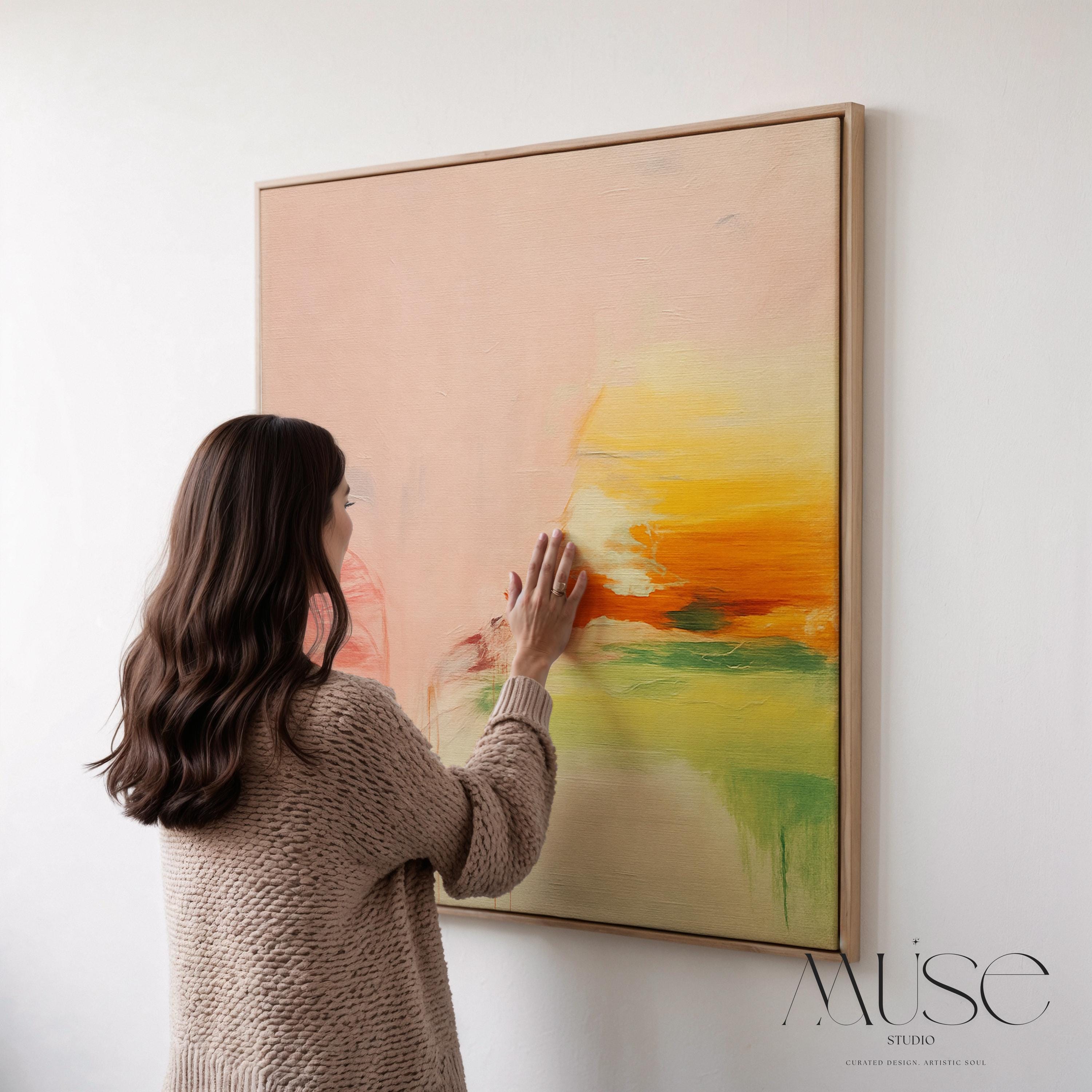 Square abstract wall art in blush pink, soft peach, golden ochre, and fresh green tones, featuring gentle painterly blends and subtle drips. Styled in a natural wood floater frame, the piece reflects soft contemporary and warm minimal design, ideal for bedrooms, living rooms, or calming modern interiors. Gallery-wrapped framed canvas by Muse Studio.