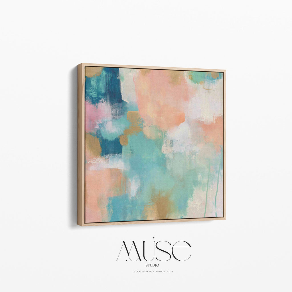 Large square abstract framed canvas wall art featuring coral, peach, teal, aqua blue, and warm sand tones layered over a soft cream background, styled above a neutral sofa, adding soft color contrast and airy painterly texture to a curated living space.