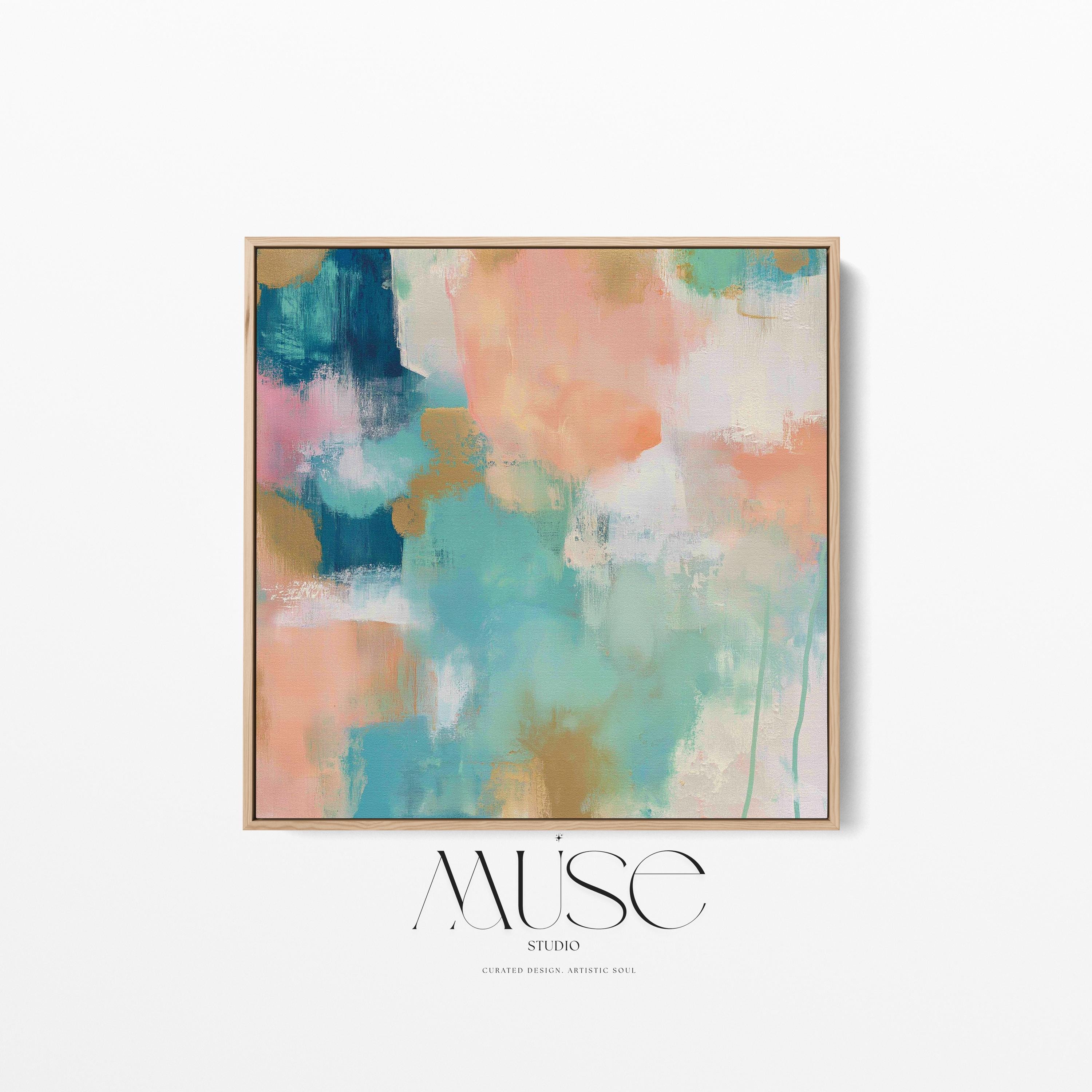 Large square abstract framed canvas wall art featuring coral, peach, teal, aqua blue, and warm sand tones layered over a soft cream background, styled above a neutral sofa, adding soft color contrast and airy painterly texture to a curated living space.