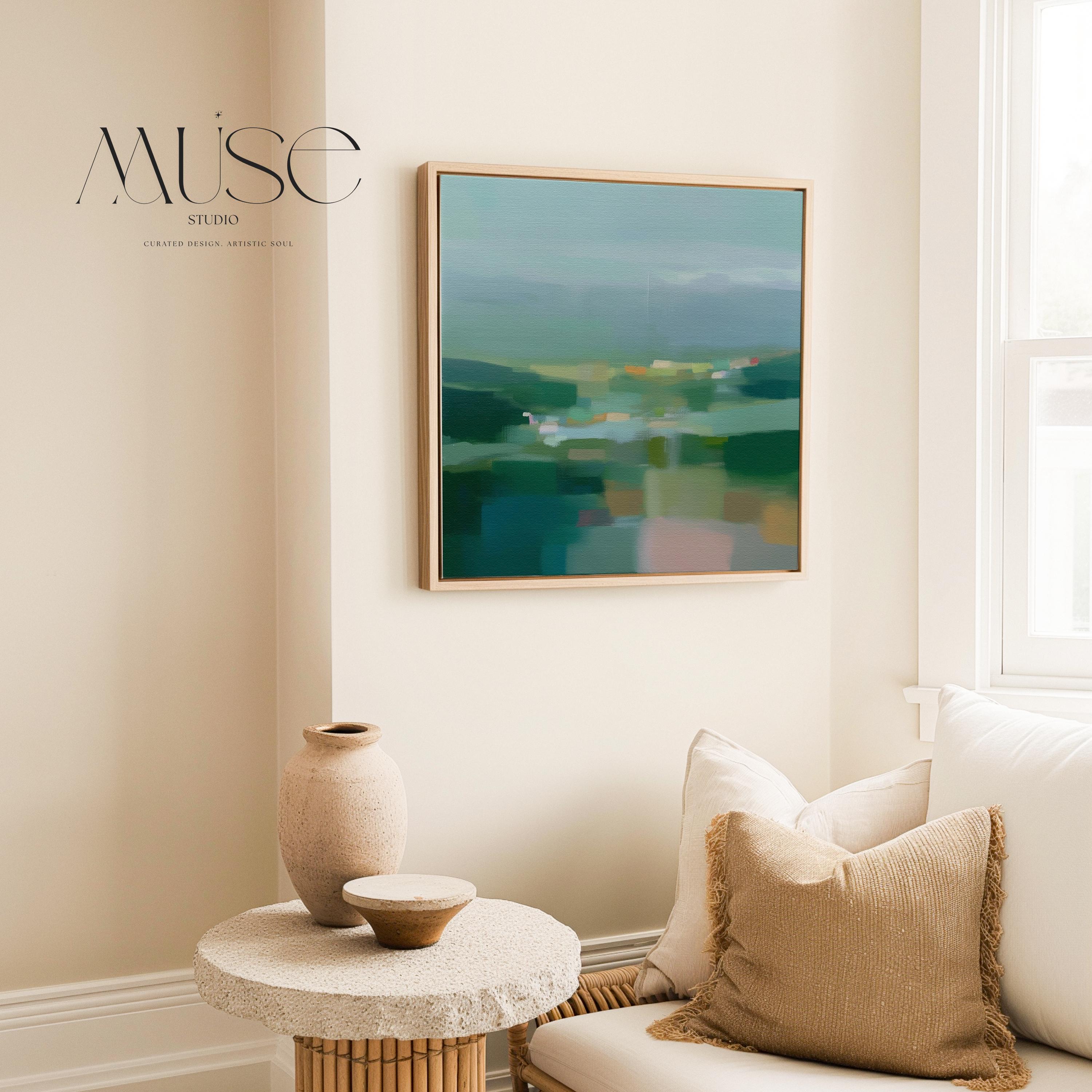 Large square framed canvas wall art in layered sage, deep green, and misty blue tones styled against a light neutral wall, creating a calm nature-inspired focal point in a refined interior.