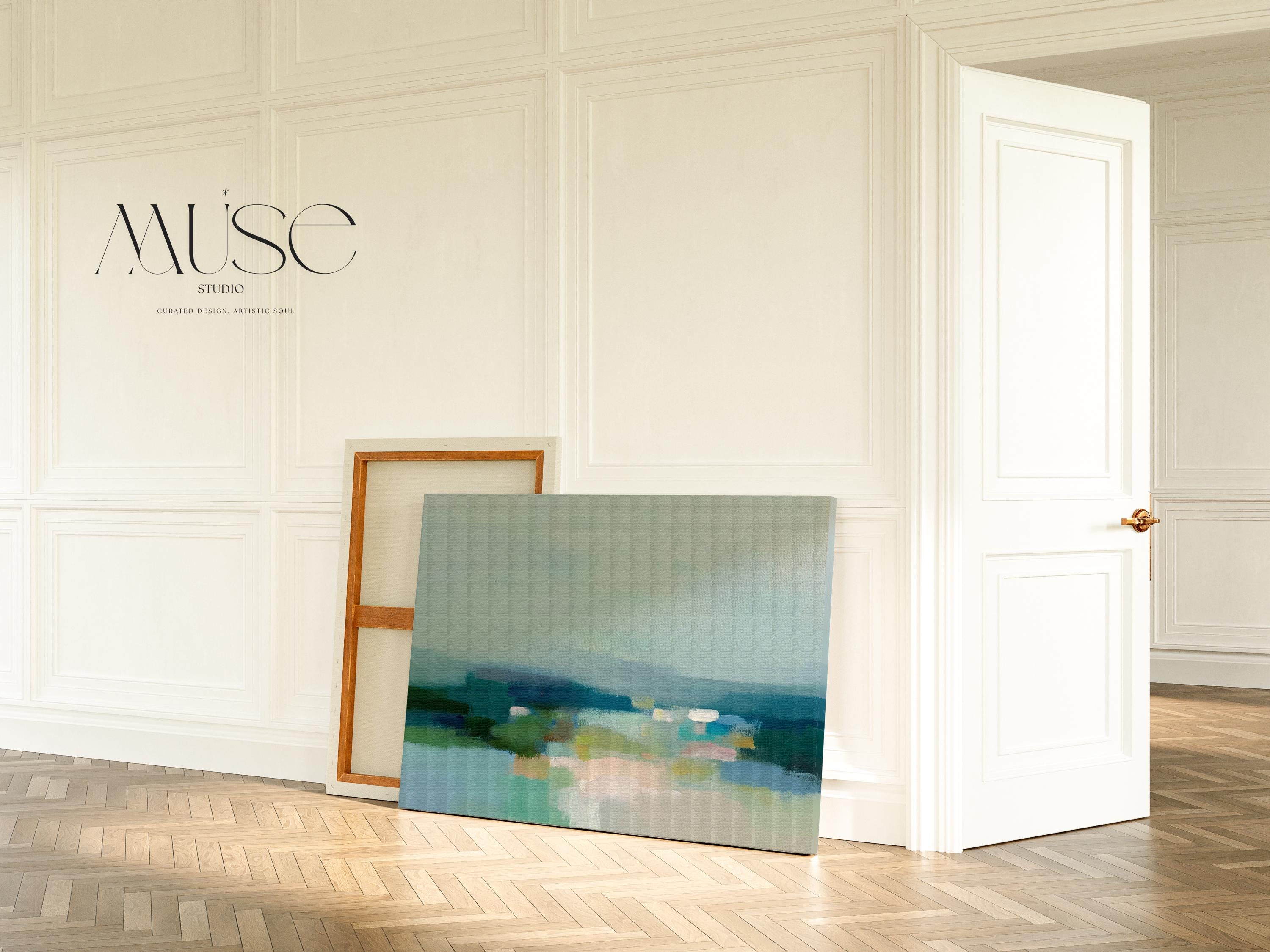 Large horizontal stretched canvas wall art in layered sage, teal, cream, and soft blue tones styled above a wood console, adding calm landscape-inspired color and airy depth to a neutral interior.