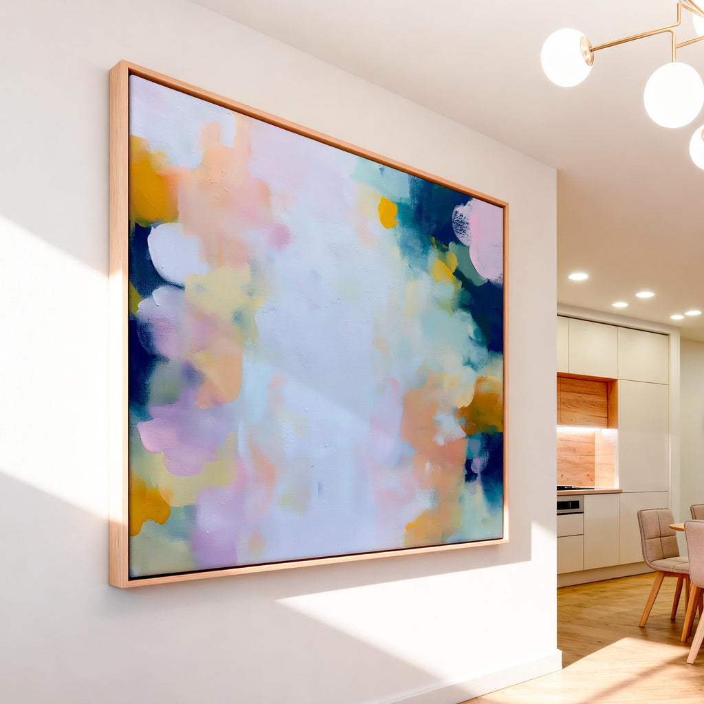 Muse Studio large horizontal framed abstract wall art printed with museum-grade giclée inks on premium gallery-wrapped canvas, featuring blush and navy pastel tones in an Organic Transitional style, styled above a linen sofa in a coastal living room.