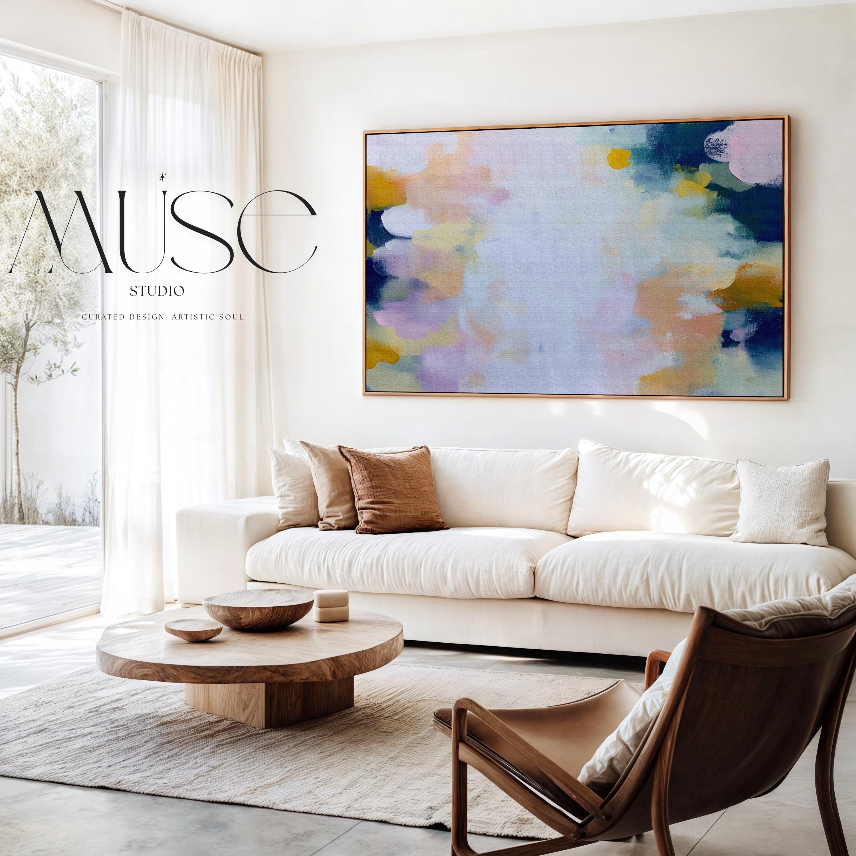 Muse Studio large horizontal framed abstract wall art printed with museum-grade giclée inks on premium gallery-wrapped canvas, featuring blush and navy pastel tones in an Organic Transitional style, styled above a linen sofa in a coastal living room.
