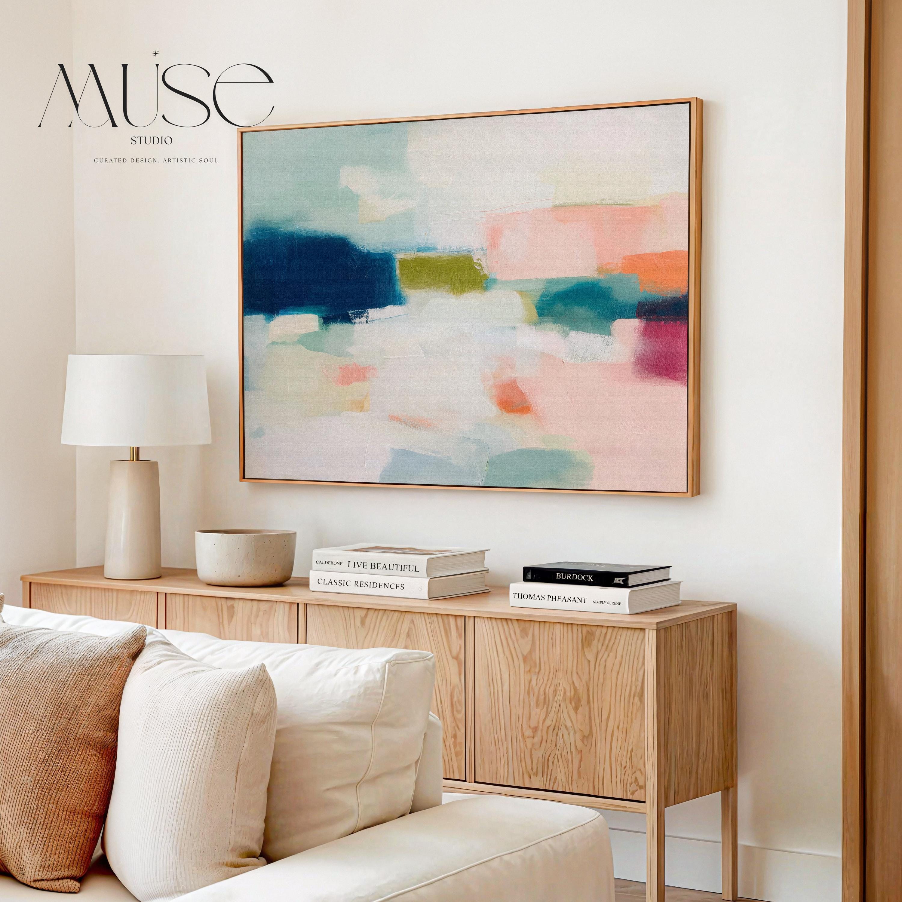 Large horizontal abstract framed canvas wall art featuring deep navy blue, muted aqua, soft blush pink, olive green, coral accents, and layered white brushstrokes, styled above a neutral sofa in a modern coastal living room, offering balanced contrast and refined contemporary color.