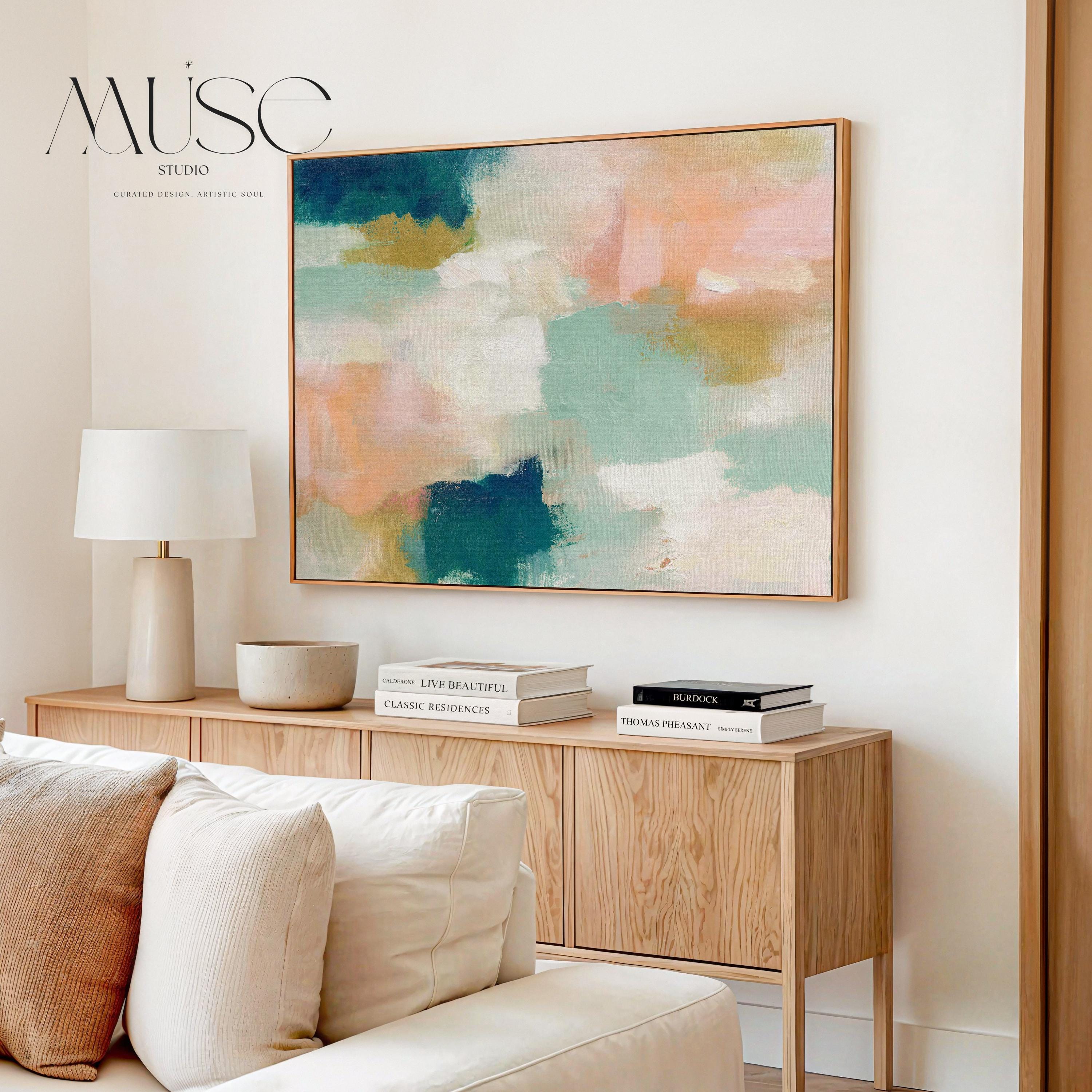 Large horizontal abstract framed canvas wall art featuring deep teal, mint green, soft peach, warm sand, and layered cream brushstrokes, styled above a neutral sofa, adding soft contrast and airy color balance to a curated living room.
