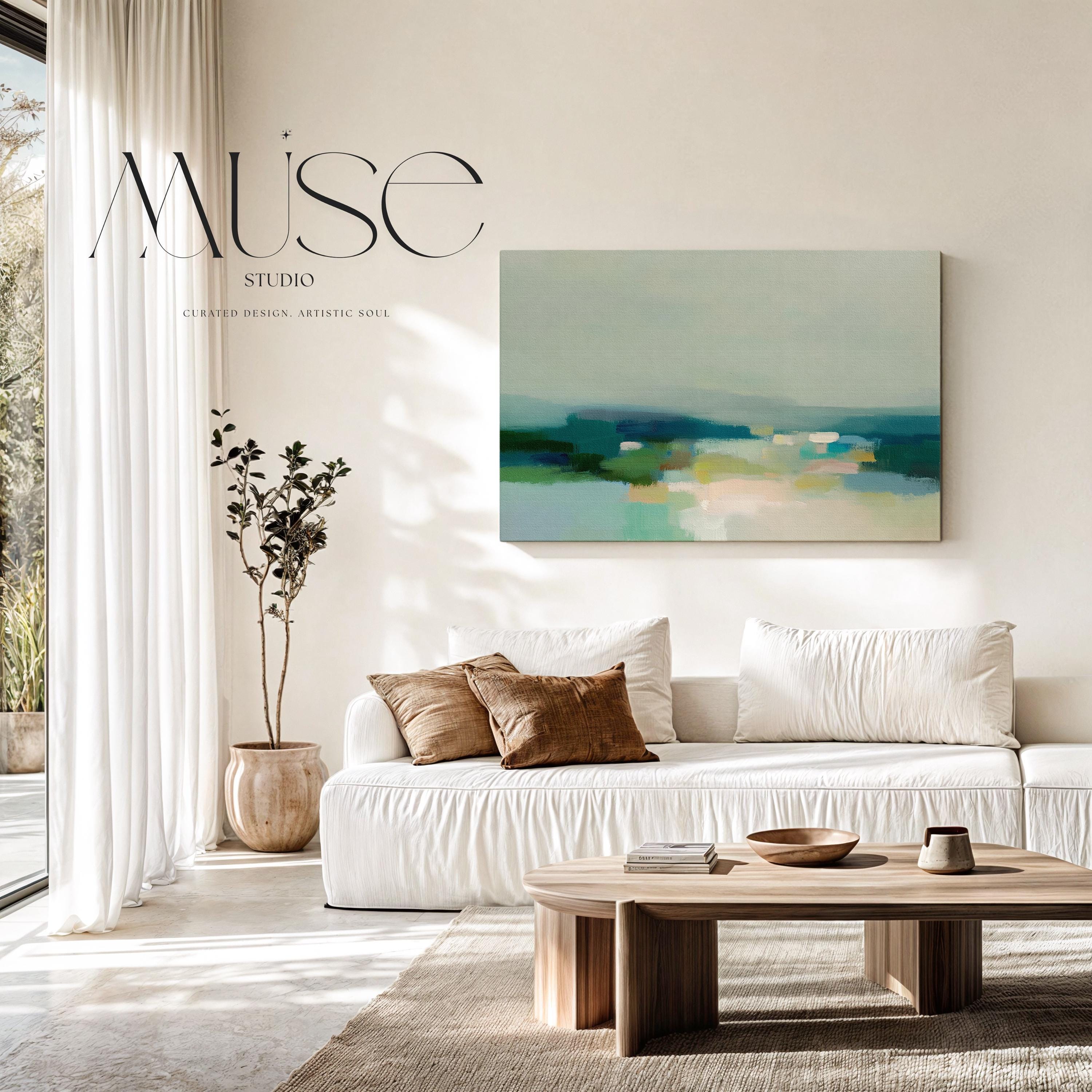 Large horizontal stretched canvas wall art in layered sage, teal, cream, and soft blue tones styled above a wood console, adding calm landscape-inspired color and airy depth to a neutral interior.