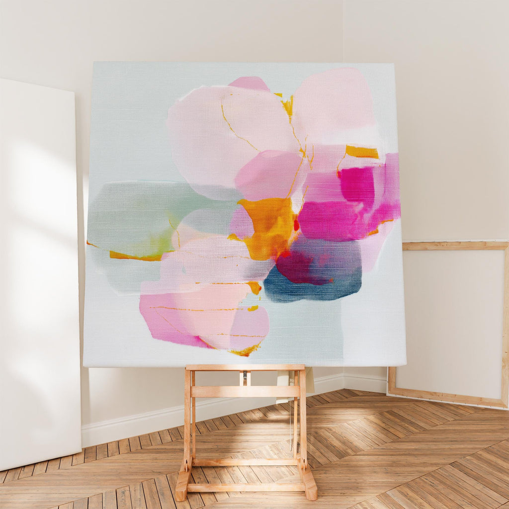 First Bloom 1052 by Muse Studio large square floral canvas wall art featuring blush pink, magenta, soft blue, and golden ochre abstract blooms printed with museum-grade giclée inks on premium gallery-wrapped artist canvas for Romantic Botanical bedrooms and bright contemporary interiors.
