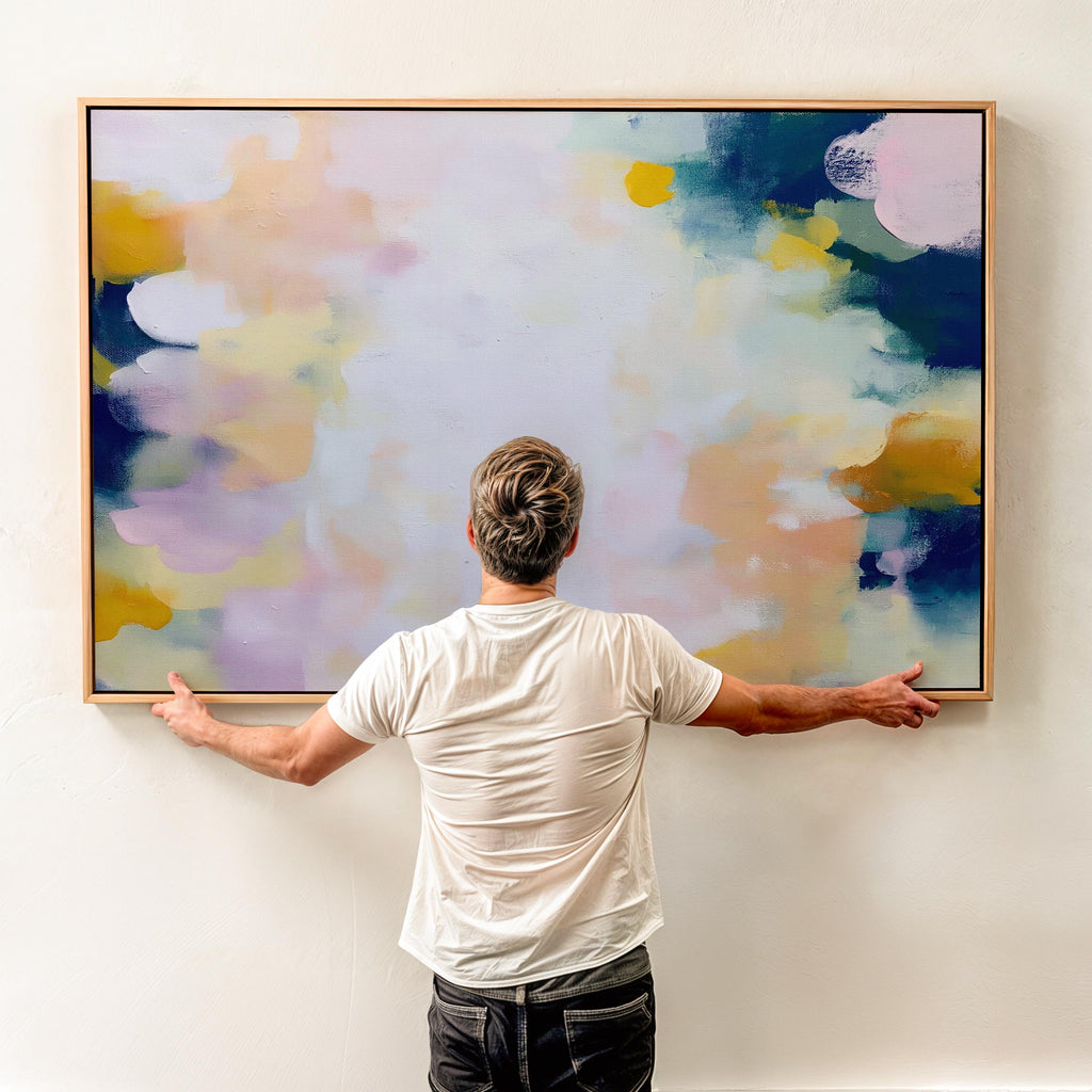 Muse Studio large horizontal framed abstract wall art printed with museum-grade giclée inks on premium gallery-wrapped canvas, featuring blush and navy pastel tones in an Organic Transitional style, styled above a linen sofa in a coastal living room.