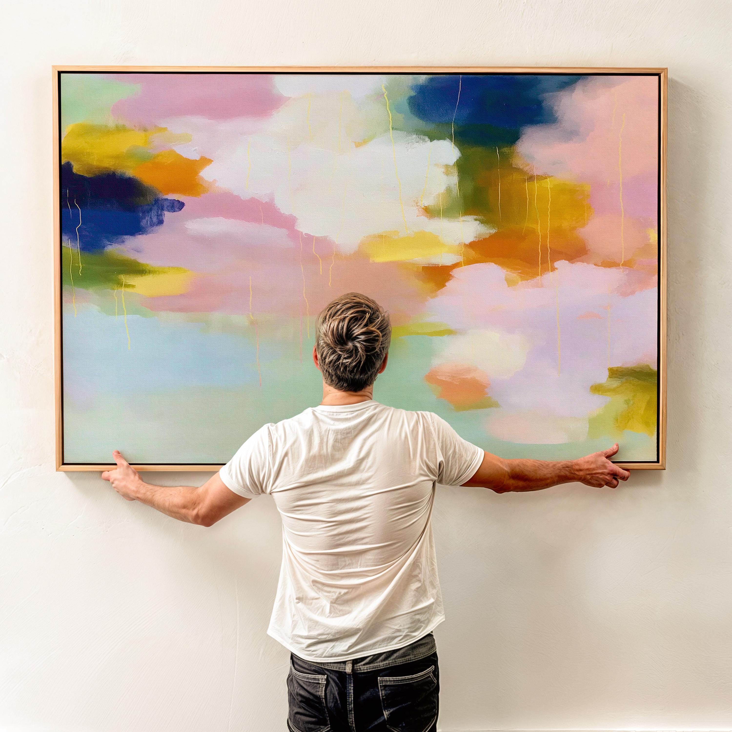 Blush Crescendo No. 291 by Muse Studio & Co. large horizontal pastel abstract framed canvas wall art in blush pink, teal and cream tones printed with museum-grade giclée inks on premium gallery-wrapped artist canvas with custom float frame options in natural, white, black, antique gold or antique silver, styled above a sofa in a soft contemporary living room.