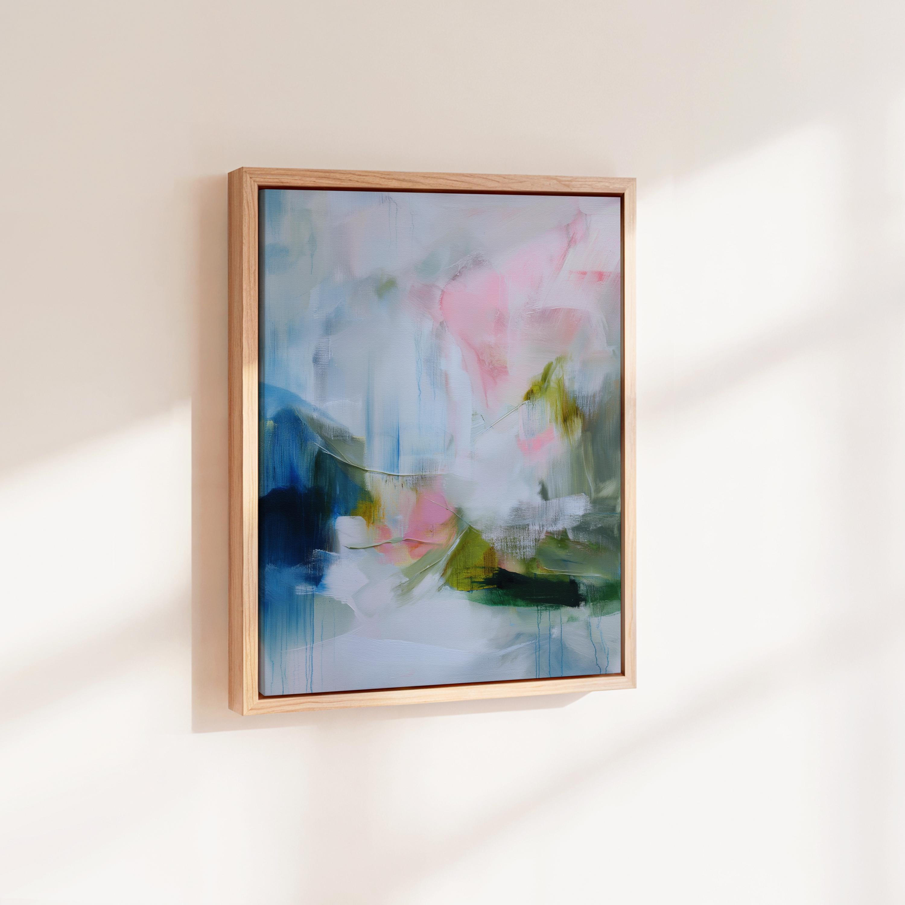 Spring Showers No. 1061 by Muse Studio & Co. vertical abstract wall art in blue, blush pink, and green tones, printed with museum-grade giclée inks on premium gallery-wrapped canvas and framed in natural wood float frame, styled in a serene bedroom above bed in soft contemporary interior.