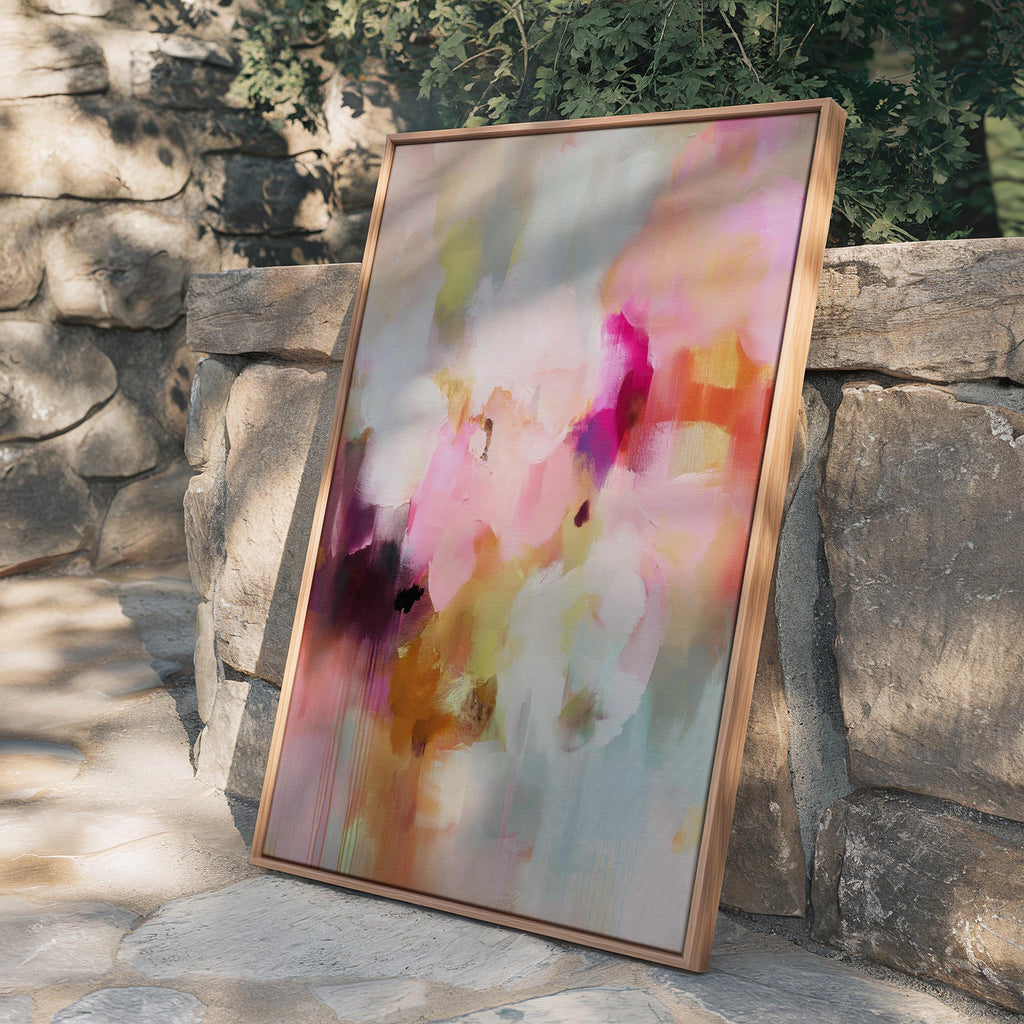 Spring Showers No. 1061 by Muse Studio & Co. vertical framed abstract wall art in blush pink, coral, ochre, and soft aqua tones, printed with museum-grade giclée inks on premium canvas and finished in a natural wood float frame, styled in a boho living room with warm neutral textures and layered decor.