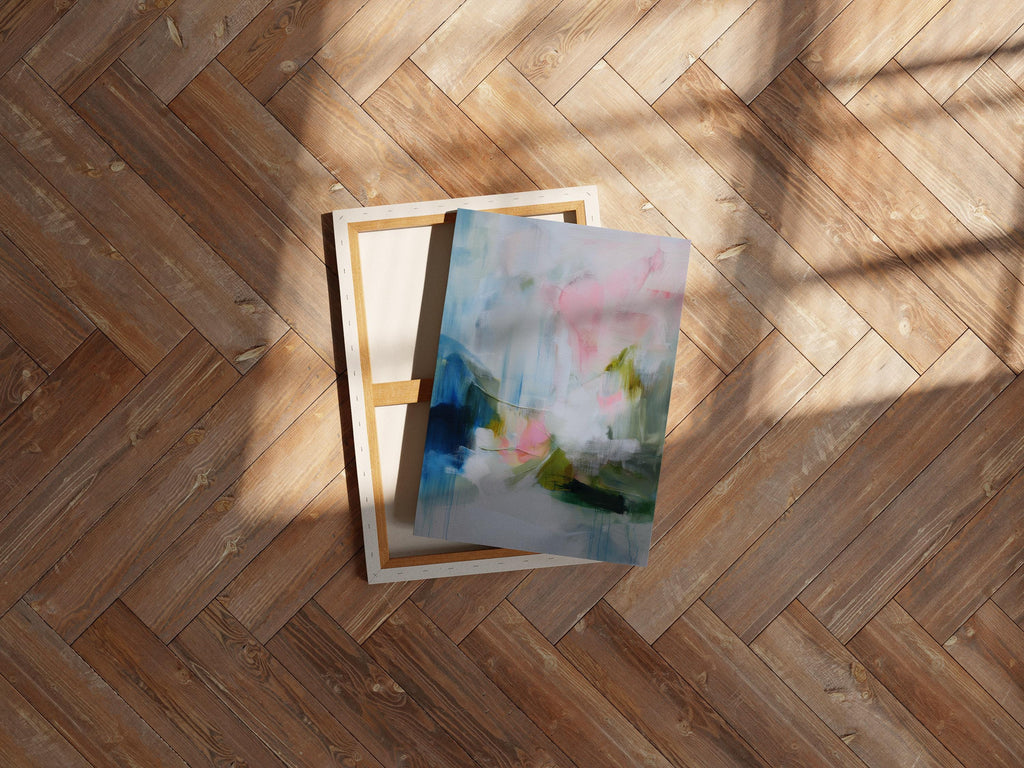 Spring Showers No. 1061 by Muse Studio & Co. vertical abstract canvas wall art in blue, blush pink, and soft green tones with a cottage botanical style, printed with museum-grade giclée inks on premium gallery-wrapped canvas, styled above a linen bed in a romantic cottage bedroom with soft contemporary decor.