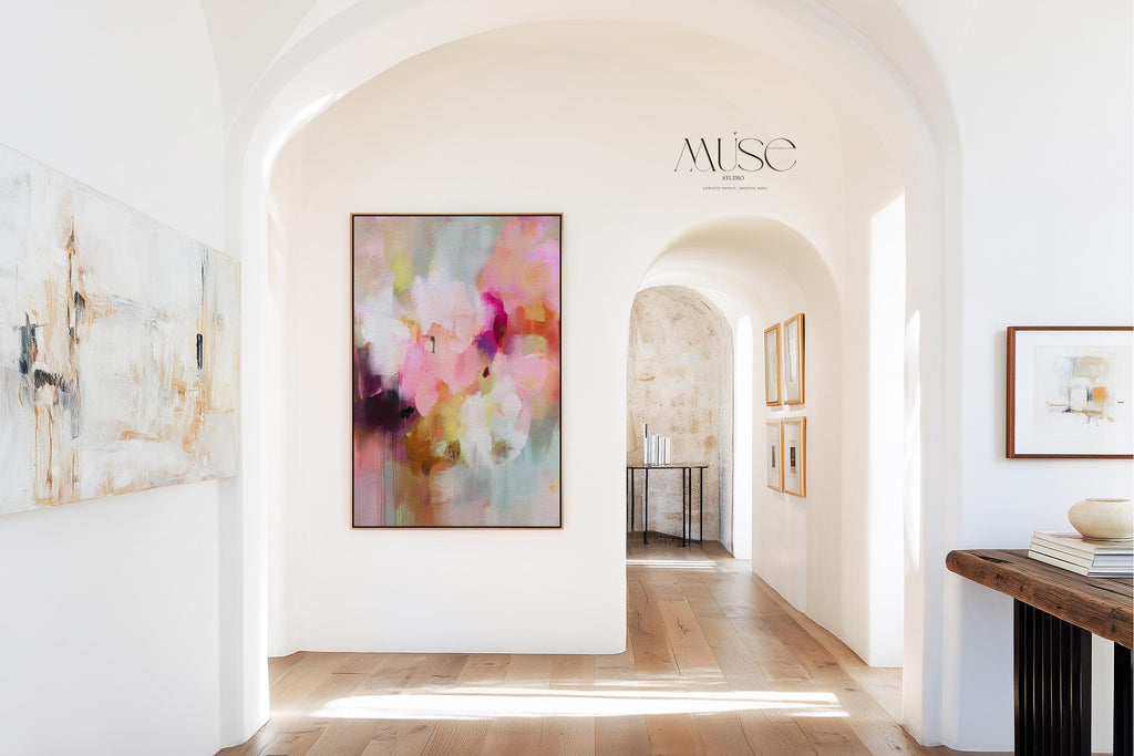 Spring Showers No. 1061 by Muse Studio & Co. vertical framed abstract wall art in blush pink, coral, ochre, and soft aqua tones, printed with museum-grade giclée inks on premium canvas and finished in a natural wood float frame, styled in a boho living room with warm neutral textures and layered decor.