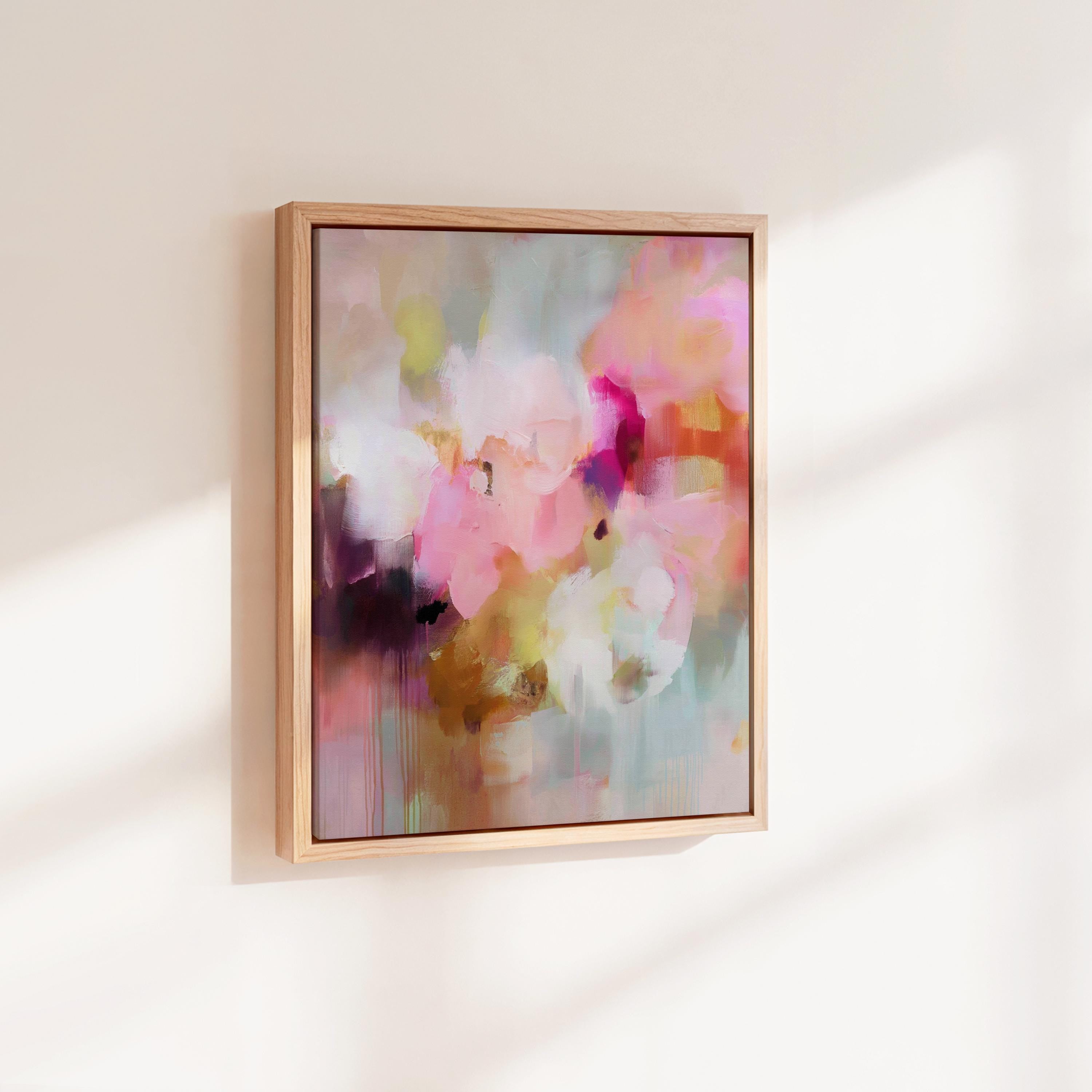 Spring Showers No. 1061 by Muse Studio & Co. vertical framed abstract wall art in blush pink, coral, ochre, and soft aqua tones, printed with museum-grade giclée inks on premium canvas and finished in a natural wood float frame, styled in a boho living room with warm neutral textures and layered decor.